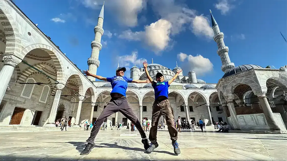 Two boys jump for joy in front of the Blue Mosque in Istanbul Turkey Family Travel Tips
