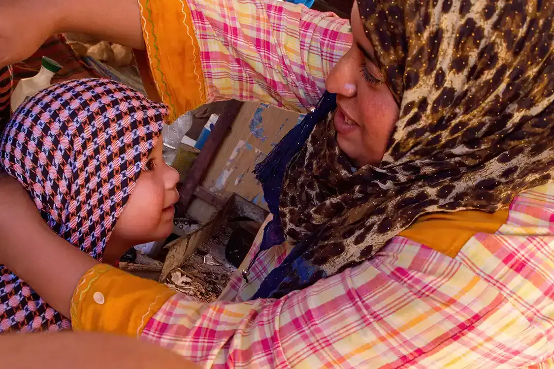 A Jordanian woman helps a young boy put on a keffiyeh