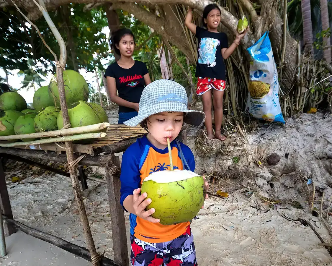 A boy drinks from a coconut on an island in the Philippines