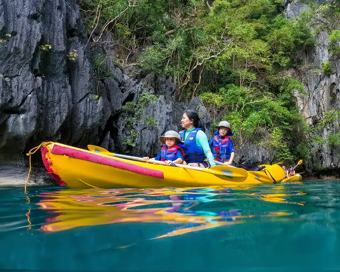 A family paddles a kayak through the bays of El Nido