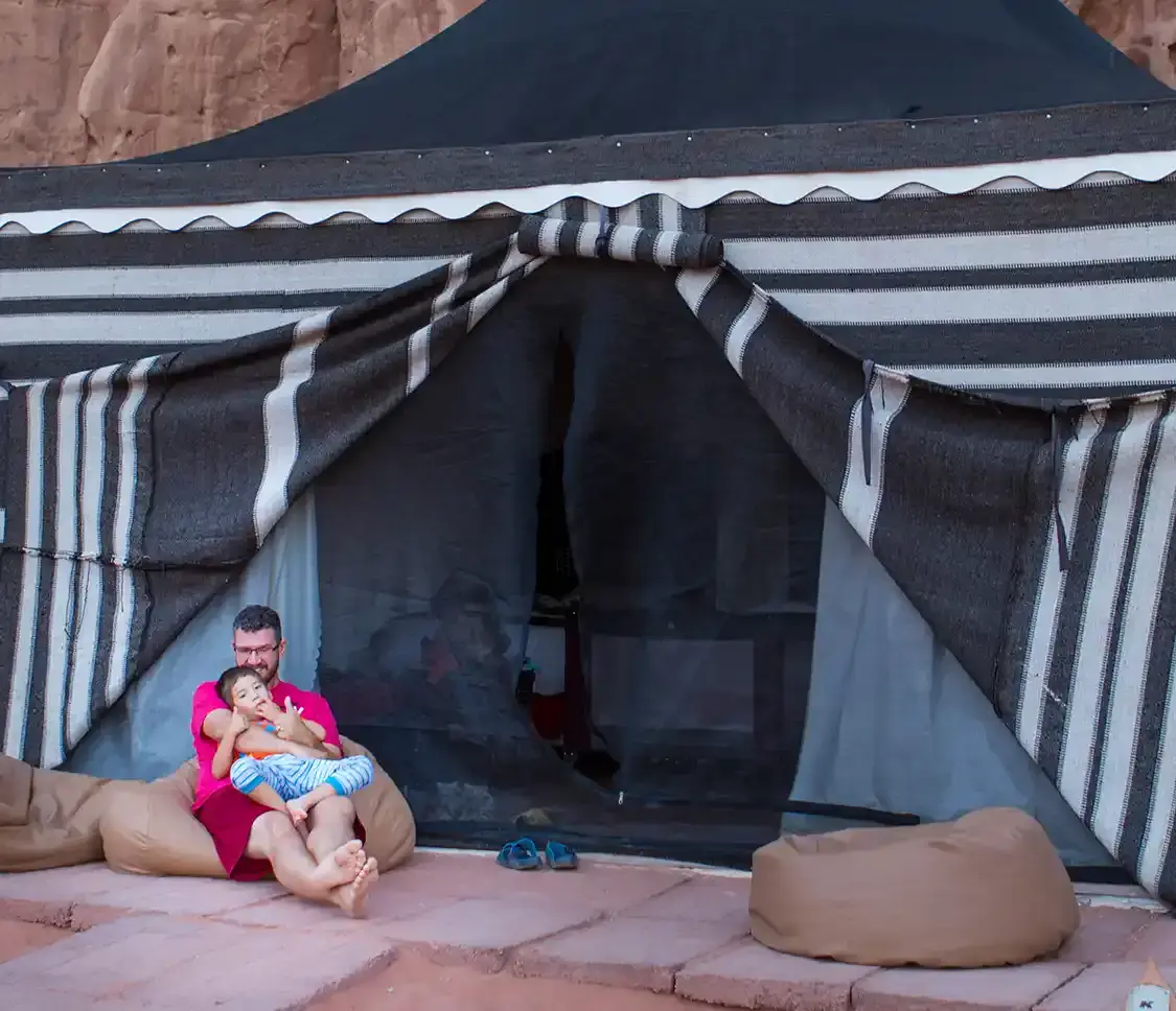 A father and his son relax outside of a glamping tent in Wadi Rum Jordan