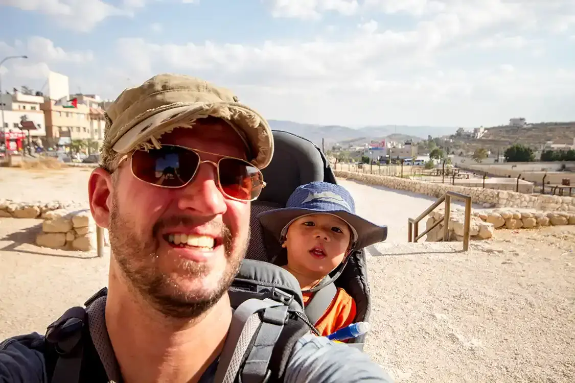A father carries his son in a child carrier through Jerash Jordan