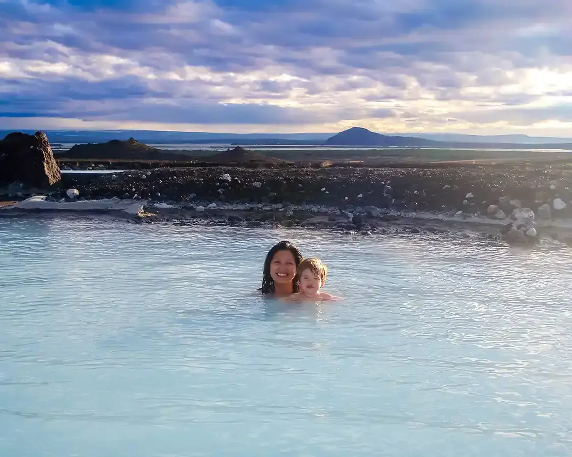 A mother and her toddler bathe in a hot spring in Myvatn Iceland