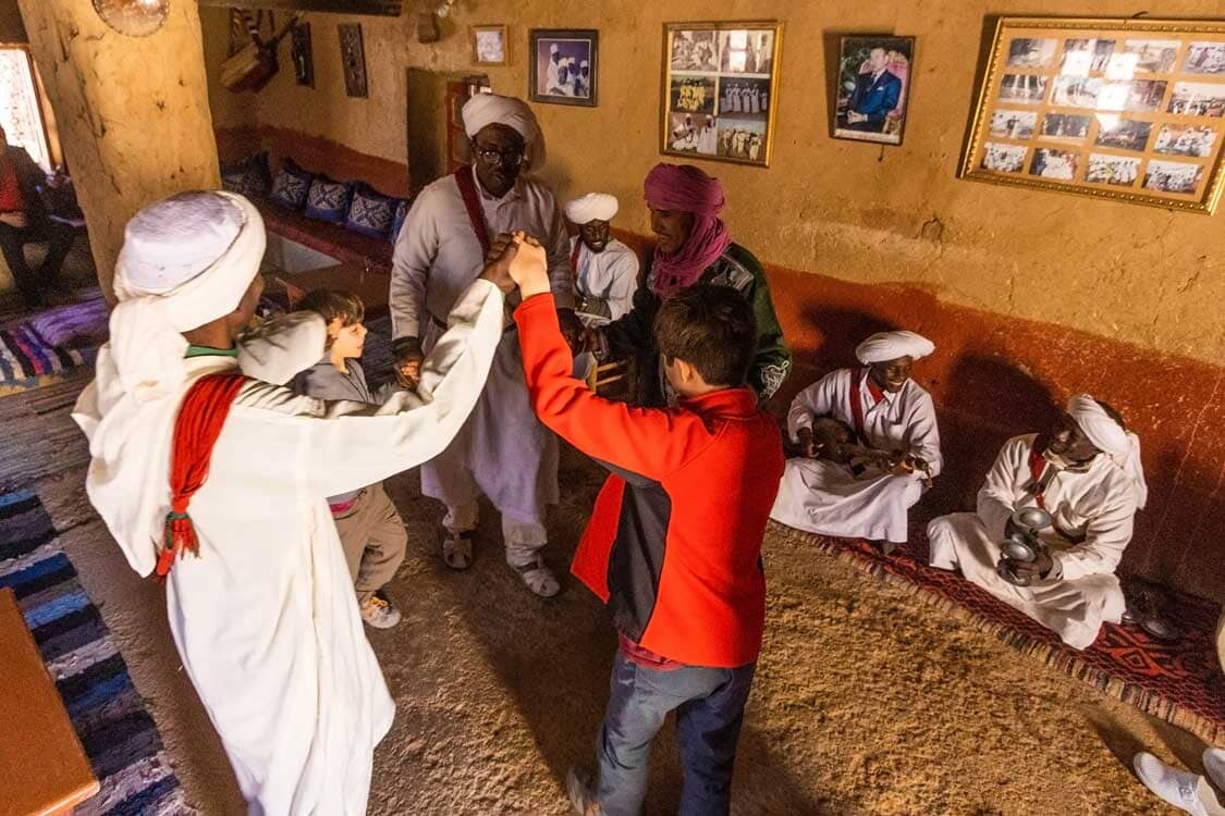 Two boys dance with Gnawa locals in Morocco