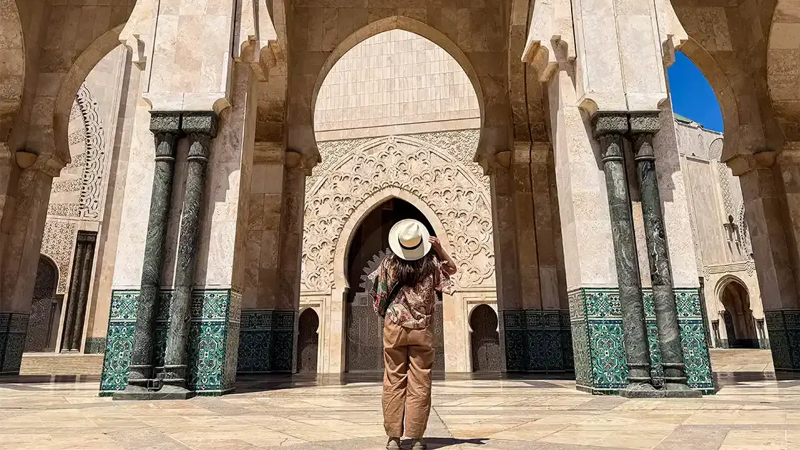 A woman looks up at a mosque entrance in Casablanca, Morocco