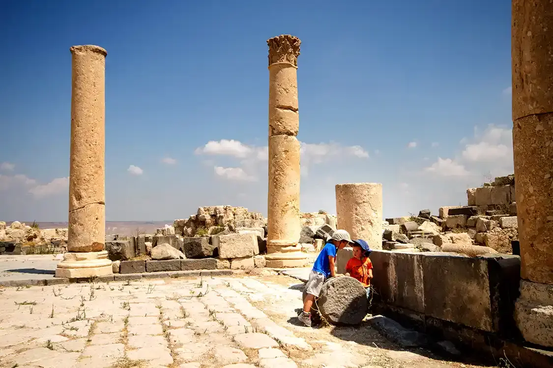 Two young boys in travel clothes at the Umm Qais ruins