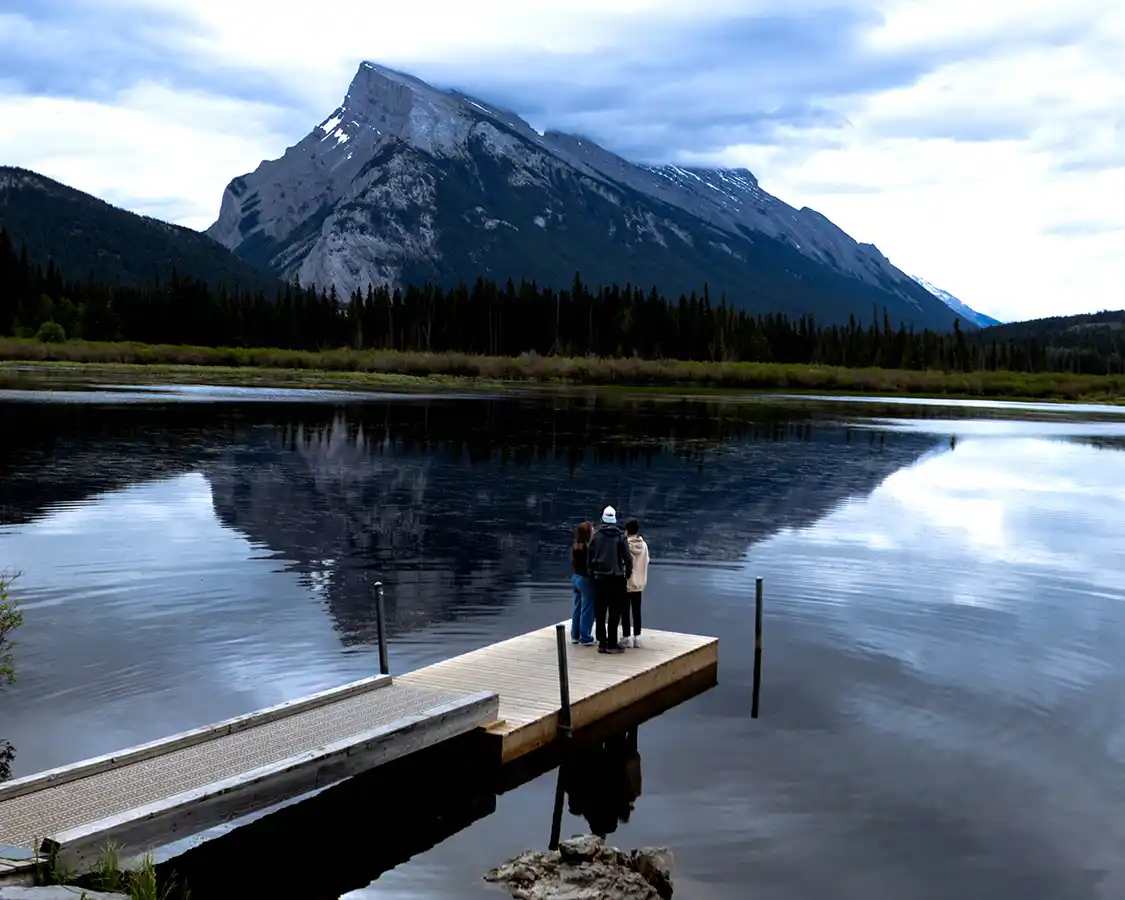 A woman and her two sons look out over Vermilion Lakes from a dock
