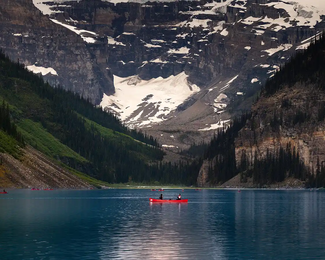 couple paddling a red canoe in the middle of Lake Louise Alberta
