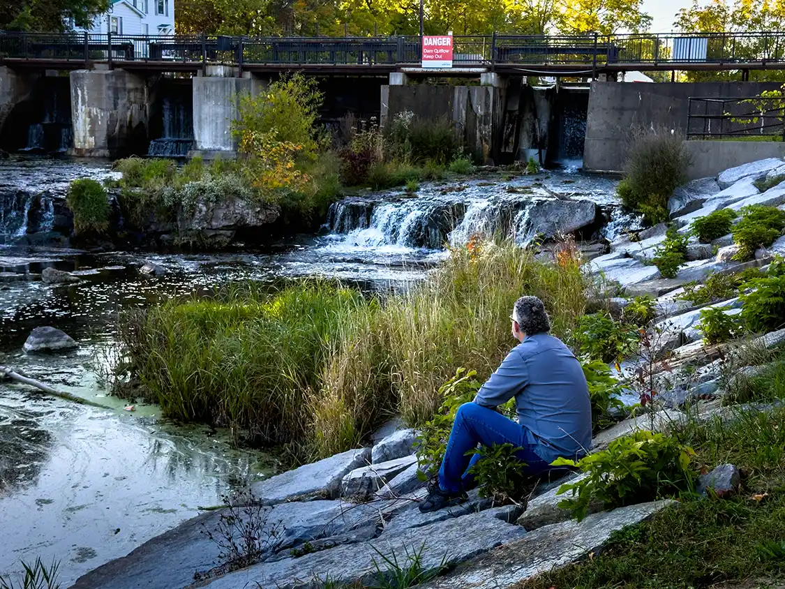 Kevin Wagar sits next to the waterfall in Confederation Park Gananoque